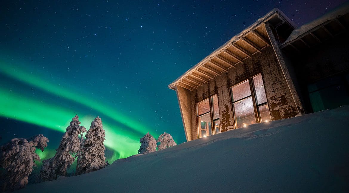Aurora boreal sobre cabaña en Octola Private Wilderness Finlandia Laponia