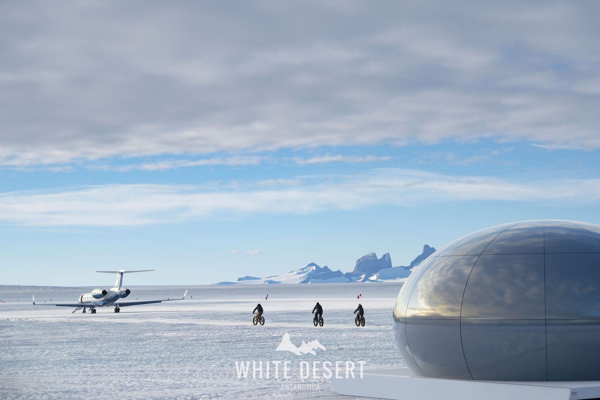 Aircraft landing strip in Antarctica and people riding bicycles in the snow.