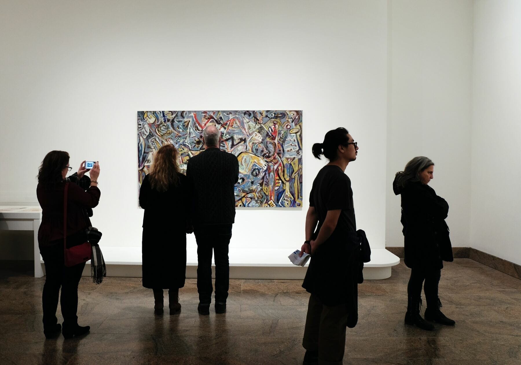 Five people looking at a painting