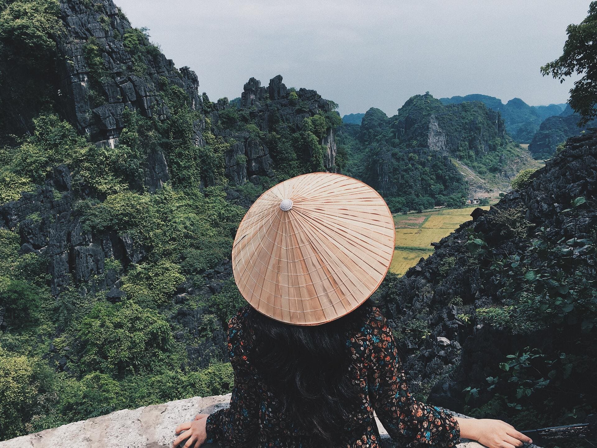 Vista de una mujer con un sombrero frente a las montañas de Vietnam